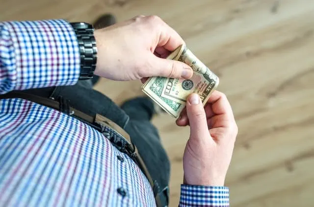 how to budget money on low income guy in a plaid shirt holding cash Middle Class Dad