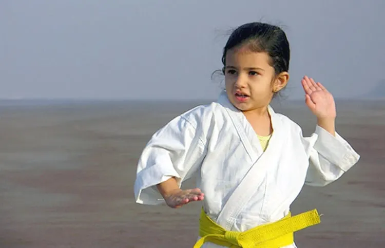 Middle Class Dad how to choose a martial arts school young girl in a karate gi with a yellow belt posing