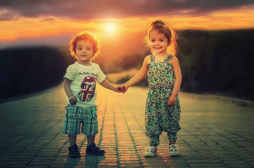 confidence building activities for kids 2 young kids holding hands, smiling, at sunset