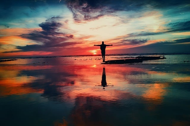 person with arms outstretched on a beach at sunset boosting self-esteem Middle Class Dad