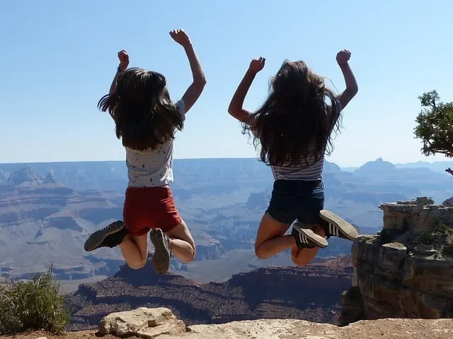 best vacation spots for tweens girls jumping at the Grand Canyon Middle Class Dad