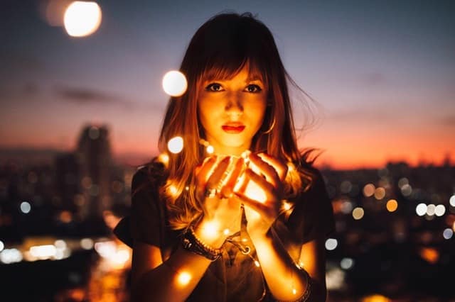 law of attraction gratitude secrets Middle Class Dad young woman holding balls of light at sunset with a city behind her