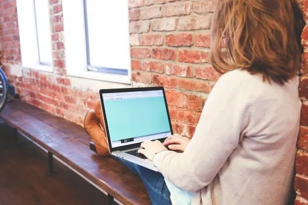 jobs college students can do online young woman on a laptop sitting on a bench next to a brick wall working on a laptop Middle Class Dad