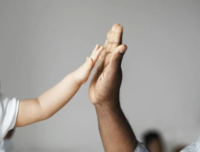 role of parents in a child’s life a small child's hand high fiving a dad's hand Middle Class Dad
