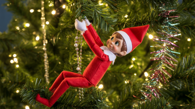 a small, mischievous Elf on the Shelf doll precariously clinging to a branch within a brightly lit Christmas tree